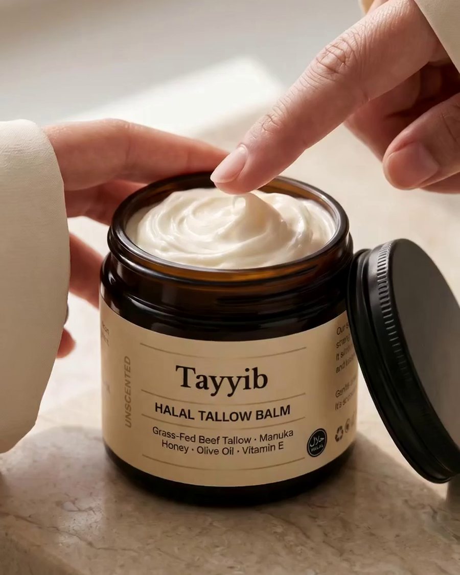 A fingertip lifting a curl of whipped balm from the open amber Tayyib jar